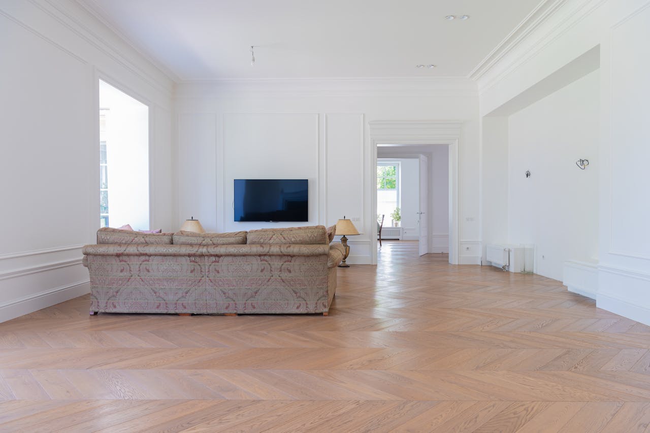 Bright, elegant living room with luxurious sofa, hardwood flooring, and wall-mounted TV.